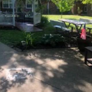 A sunny backyard with a patio, picnic table, and garden area.