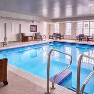 A bright indoor swimming pool area with seating and large windows.