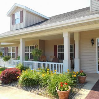 A charming house with a welcoming front porch adorned with colorful flowers.