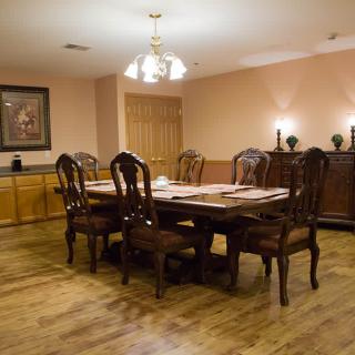 A cozy dining room with a wooden table set for a meal, featuring elegant chairs and a chandelier overhead.
