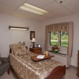 A comfortable hospital room with a single bed, bedside table, and window view.