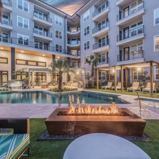 Modern apartment complex with a pool and fire pit in the evening.