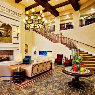 A luxurious living room featuring elegant furnishings, a grand staircase, and a stylish chandelier.
