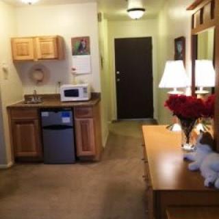 A cozy kitchenette area with wooden cabinets, a microwave, and soft lighting.
