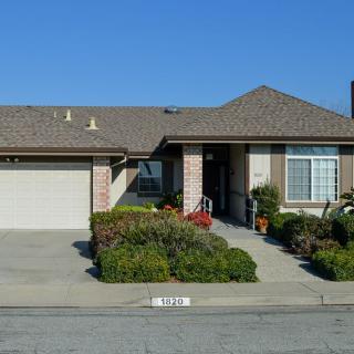 A suburban house with a well-maintained lawn and driveway under a clear blue sky.