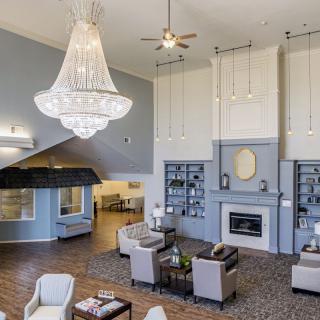 A spacious and elegantly designed living room featuring a grand chandelier, comfortable seating, and a fireplace.