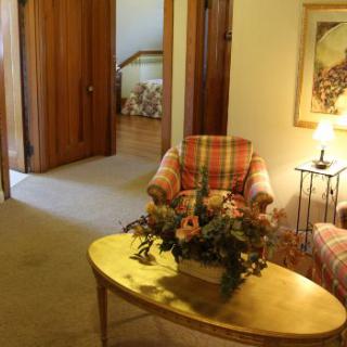 A cozy living room with patterned armchairs, a wooden coffee table with floral arrangement, and soft lighting.