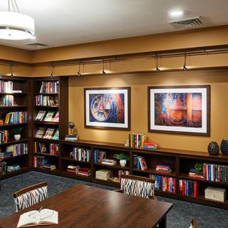 A cozy library with bookshelves and framed artwork on the walls.
