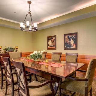 A well-decorated dining room with a wooden table, upholstered chairs, and elegant lighting.