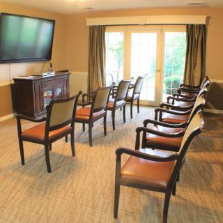 A small conference room with arranged chairs facing a television and large windows.