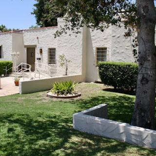 A charming house surrounded by a well-maintained garden and trees.