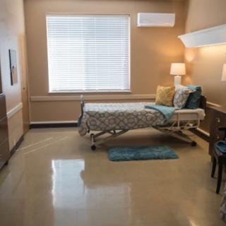 A clean and well-furnished hospital room with a single bed, dresser, and decorative elements.
