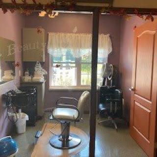 A cozy hair salon interior with a styling chair, mirror, and various hairdressing equipment.