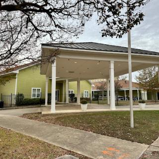 A welcoming exterior view of a green building with a spacious entrance and canopy.