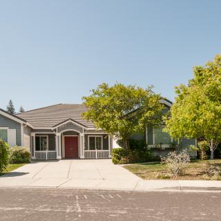 A suburban house with a driveway and surrounding trees on a sunny day.