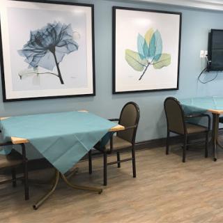 A cozy dining area featuring blue tablecloths, modern chairs, and artistic wall decor.