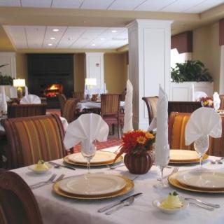 An elegantly set table in a restaurant dining area, featuring folded napkins, plates, and cutlery.