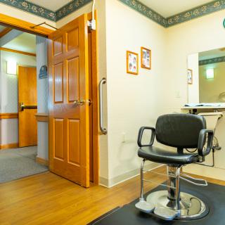 An empty hair salon interior with a styling chair and mirror.