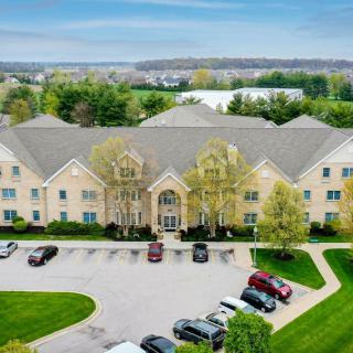 Aerial view of a large building with a parking lot and surrounding greenery.