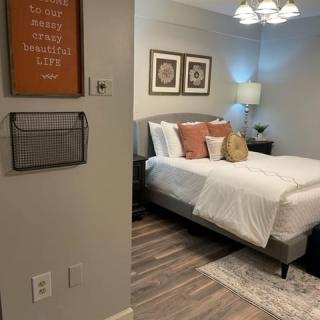 A cozy and modern bedroom featuring a neatly made bed, decorative pillows, wall art, and a bedside lamp.