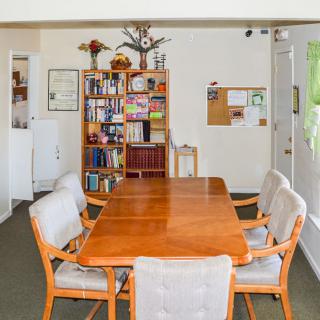 A cozy dining room with a wooden table and chairs, complemented by a bookshelf in the background.