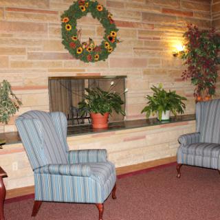 A cozy living room setup featuring two striped chairs, decorative plants, and a wreath.