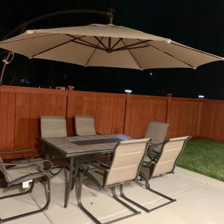 Outdoor patio set with a table, chairs, and large umbrella at night.