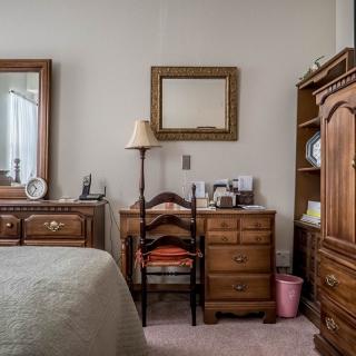 A cozy bedroom with vintage wooden furniture, including a dresser, mirror, and lamp.
