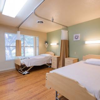 A well-lit and clean patient room in a healthcare facility, featuring two adjustable beds.