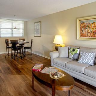A cozy living room with a sofa, coffee table, and a dining area in the background.