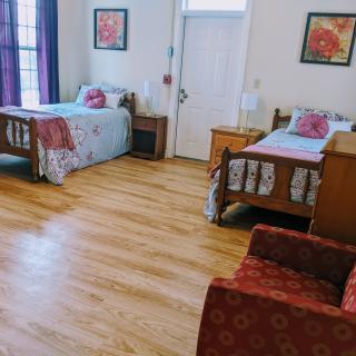 A cozy bedroom with two single beds, hardwood floors, and decorative wall art.