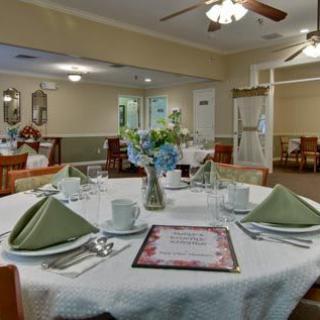 A well-arranged dining room table with neatly folded green napkins and a floral centerpiece.