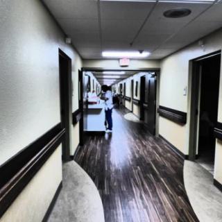 A hospital hallway with a person in a wheelchair.