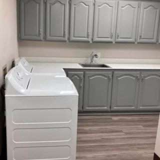 A modern laundry room with a washer, dryer, and ample cabinet space.