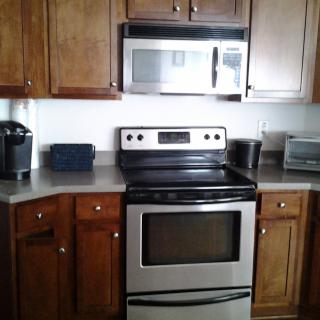 A modern kitchen with wooden cabinets, a stainless steel stove, and a microwave.