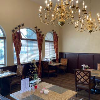 A cozy restaurant interior featuring elegant chandeliers and neatly arranged dining tables by large windows.