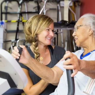 A supportive trainer assists an elderly person during a workout session.