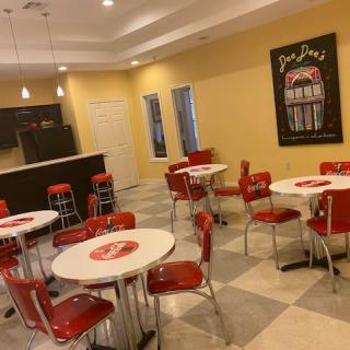 A retro-style diner with red chairs and white tables, featuring vintage decor.