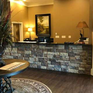A warmly lit hotel reception area with a stone-front desk and decorative elements.