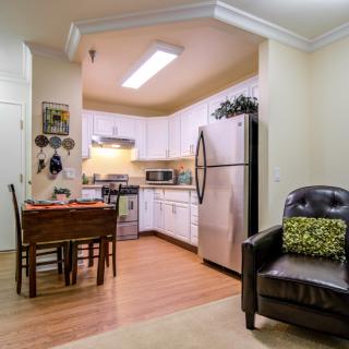 A cozy kitchen with a dining area featuring wooden floors and a modern refrigerator.