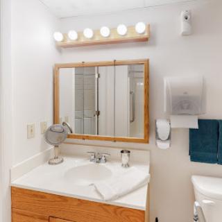 A clean and well-lit bathroom vanity area with a mirror, sink, and modern fixtures.