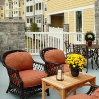 A cozy outdoor patio area with wicker chairs and a wooden table, adorned with vibrant flowers.
