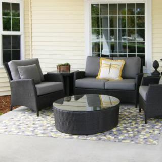 A cozy outdoor seating area on a patio with armchairs, a sofa, and a round coffee table.