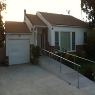 A small residential house with a ramp leading to the front entrance and an attached garage.