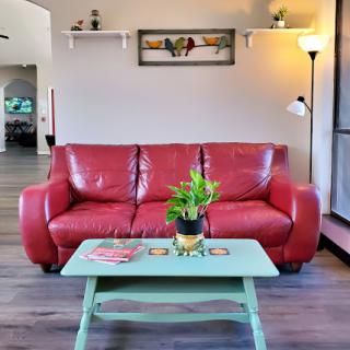A cozy living room featuring a vibrant red sofa, a mint green coffee table with a potted plant, and warm lighting.