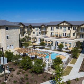 Aerial view of a modern apartment complex with a central swimming pool and landscaped gardens.