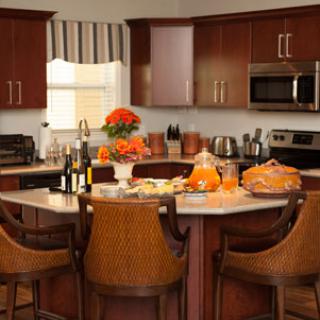 A cozy kitchen with wooden cabinets, modern appliances, and a dining island decorated with pumpkins and flowers.