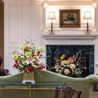 An elegantly decorated living room featuring a cozy fireplace and colorful floral arrangements.