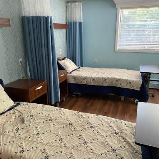 A cozy shared bedroom with two beds, dressed in patterned bedding and surrounded by curtains in a calming blue environment.