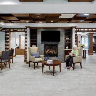 A modern living room with comfortable seating and a fireplace, featuring a TV mounted above.